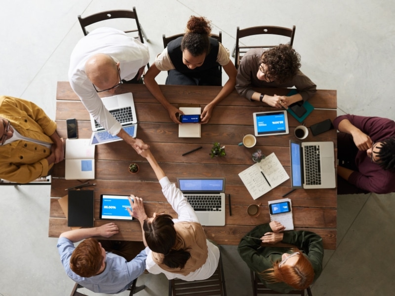 Team discussing campaign strategy for digital marketing and white label ads services around a wooden table.